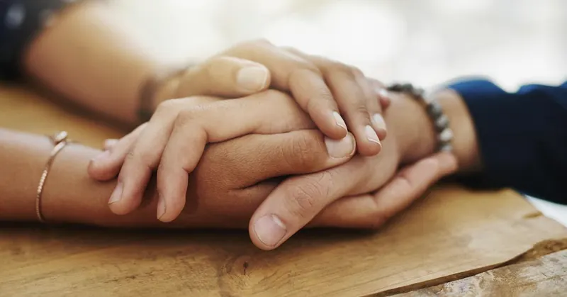 One hand resting over another in a gesture of support