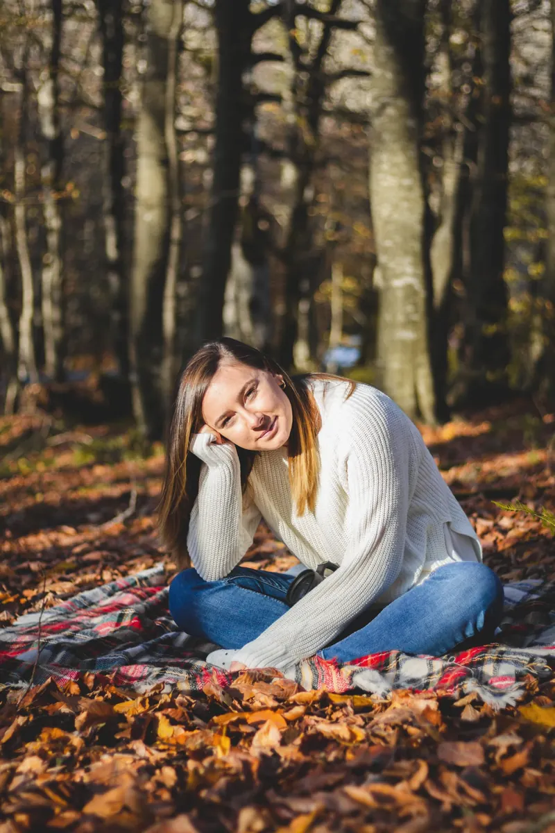 A young woman sitting thoughtfully among autumn leaves in the woods