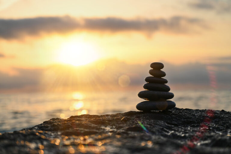 Peaceful balance of stones at sunset by the tranquil sea creating a serene atmosphere near the horizon
