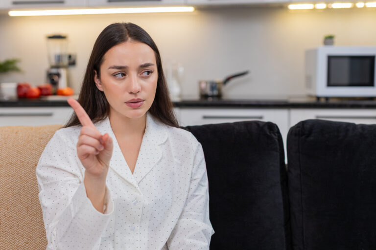 Young woman waves finger no sign disagrees refuses idea shows disapproval firm gesture stop warning