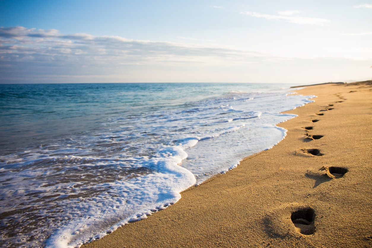 close up of footprints in the sand on the beach at sunset